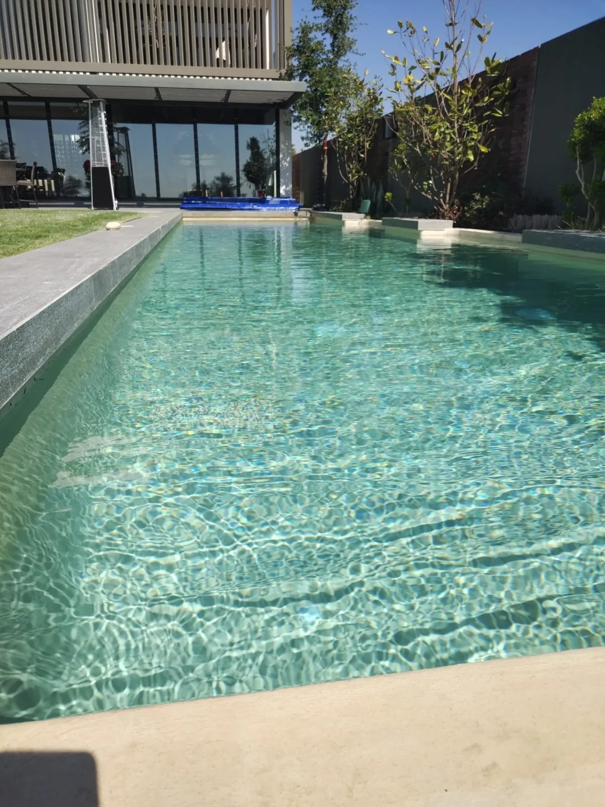 Piscina turquesa frente a una casa moderna